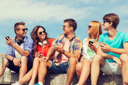 group of smiling friends with smartphones outdoors © Syda Productions