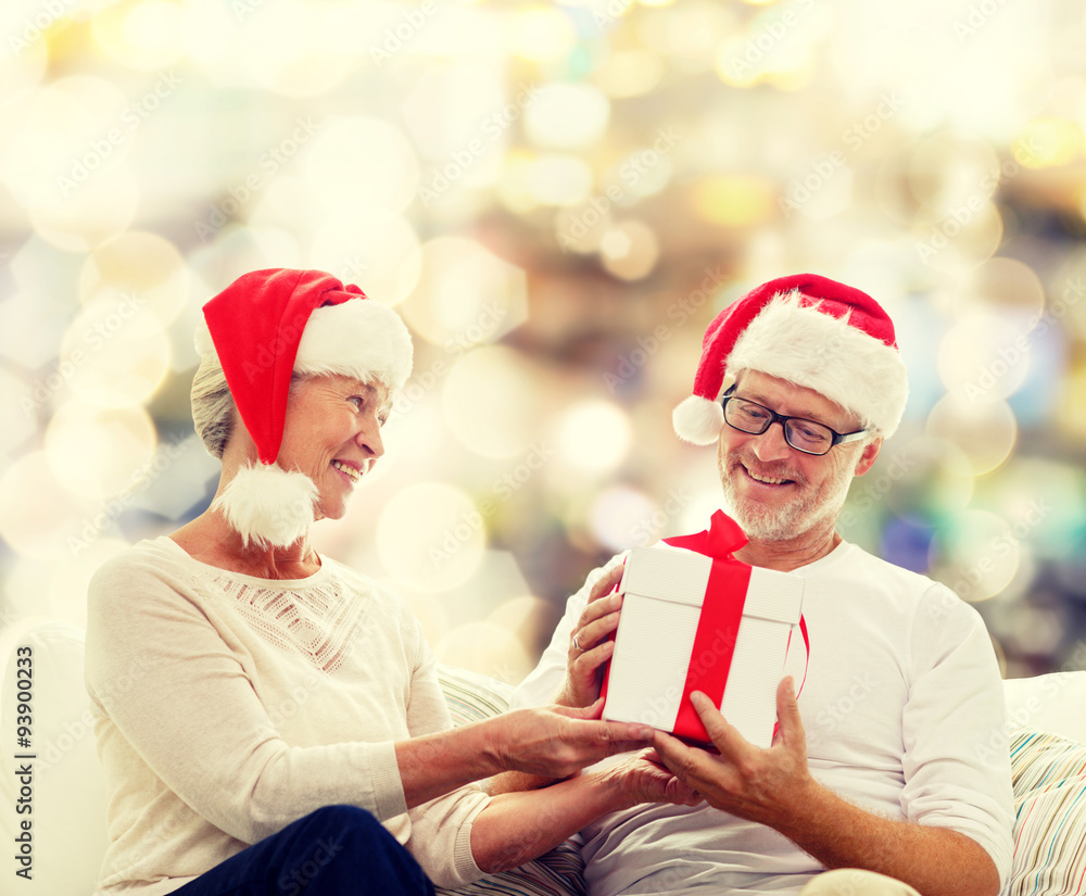 Fototapeta premium happy senior couple in santa hats with gift box