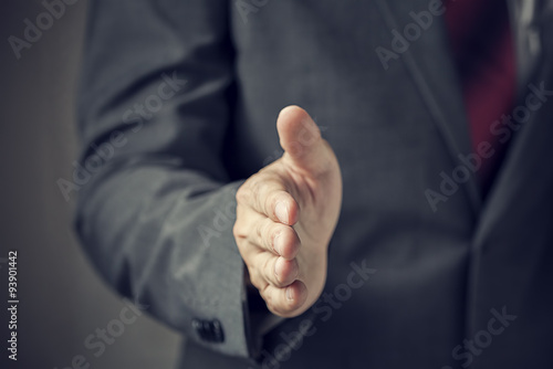 Businessman in suit ready to handshake with trust and professionalism (focus on hand, blur out the suit). It indicates many aspects such as business,finance, friendship, partnership, togetherness.