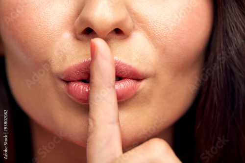 Tableau sur toile close up of young woman holding finger on lips