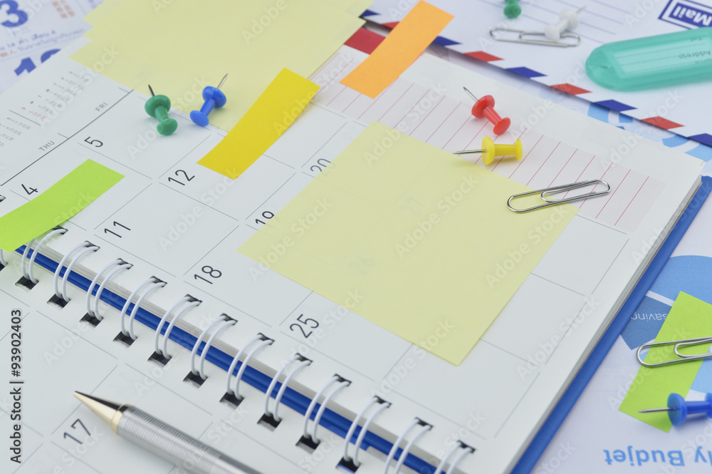 Clip with colorful sticky notes, pen and pin on business diary