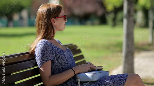 Young woman dislike reading a book and sitting on a bench