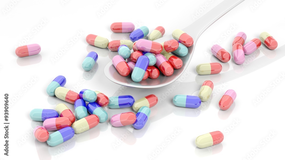 Colorful caplets inside a spoon and out, isolated on white background. Colorful caplets inside a spoon and out, isolated on white background.