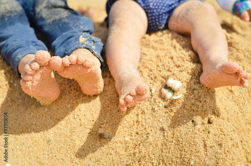 Closeup of two children's legs barefoot on summer sand seashore photo