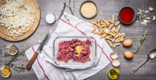preparation of raw minced meat balls with egg breadcrumbs eggs paste tomato sauce, garlic herb seasoning knife sliced onions Cooking Concept on wooden background top view 