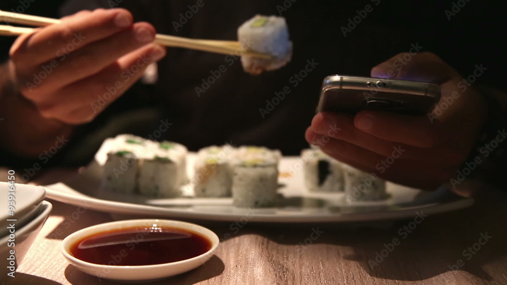 business man eating sushi and at the same time chatting with his phone at japanese restaurant business man eating sushi and at the same time chatting with his phone at japanese restaurant