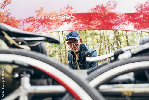 Active senior man at trunk of car. Going for a bicycle tour.