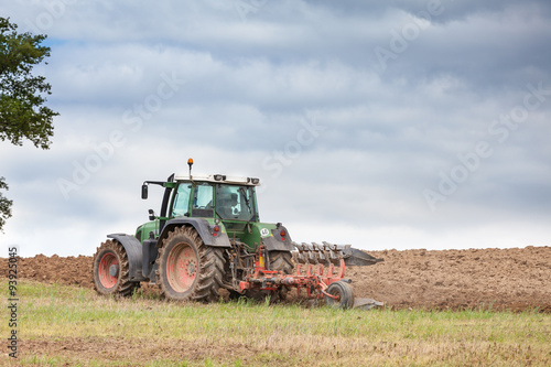 Obraz na plátně Farmer ploughing overwintered fields with a tractor and plough preparing the ear