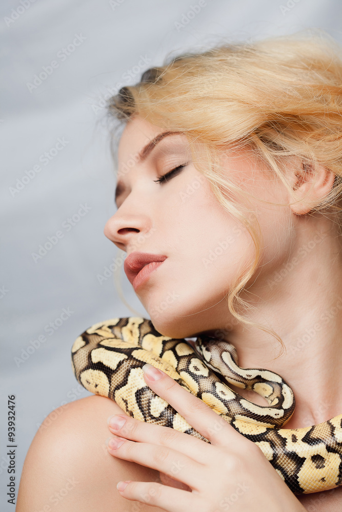 Naklejka premium Beautiful girl holding a python, which wraps around her body