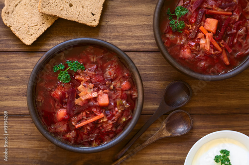 Vegetarian Borscht soup of Ukrainian origin made of beetroot, carrot, cabbage, potato, onion and celery in rustic bowls, photographed with natural light (Selective Focus, Focus on the soup)