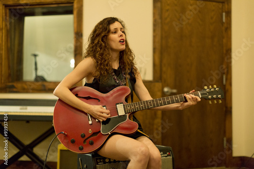 Young woman playing electric guitar at recording studio