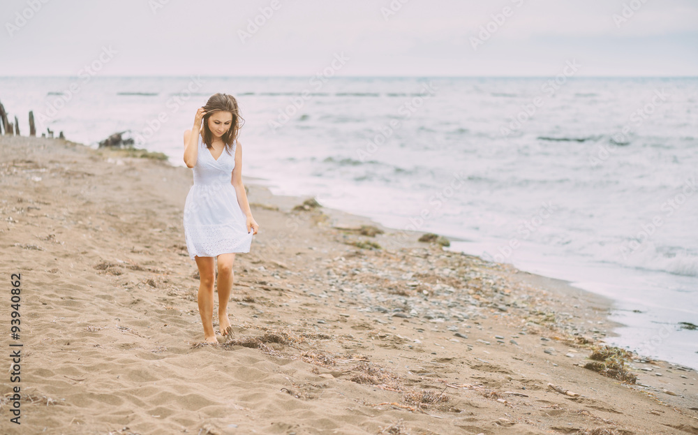 Beautiful young woman walking on beach