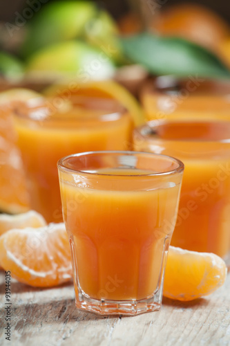Fresh tangerine juice with slices of mandarin on old wooden back