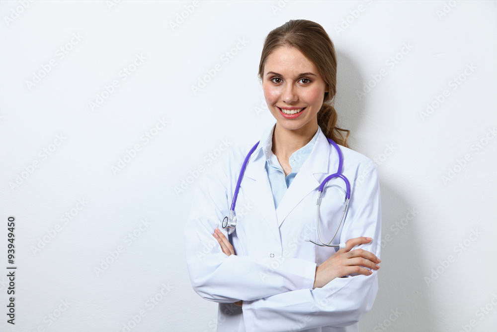 Friendly smiling young female doctor, standing near wall Friendly smiling young female doctor, standing near wall
