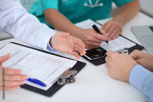 Doctors and patient sitting at the table, arms