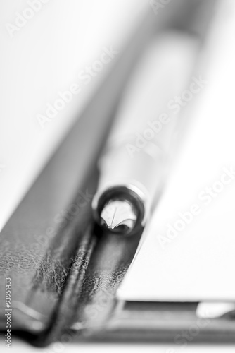 Closeup of elegant ink pen lying in the middle of an open folder