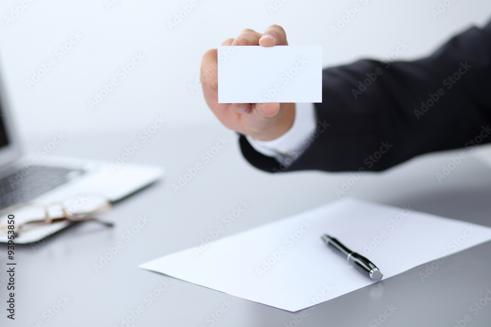 Closeup of businessman giving a business card, sitting at the table Closeup of businessman giving a business card, sitting at the table