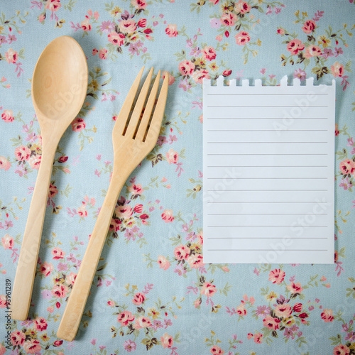 spoon, fork and empty paper on vintage style tablecloth