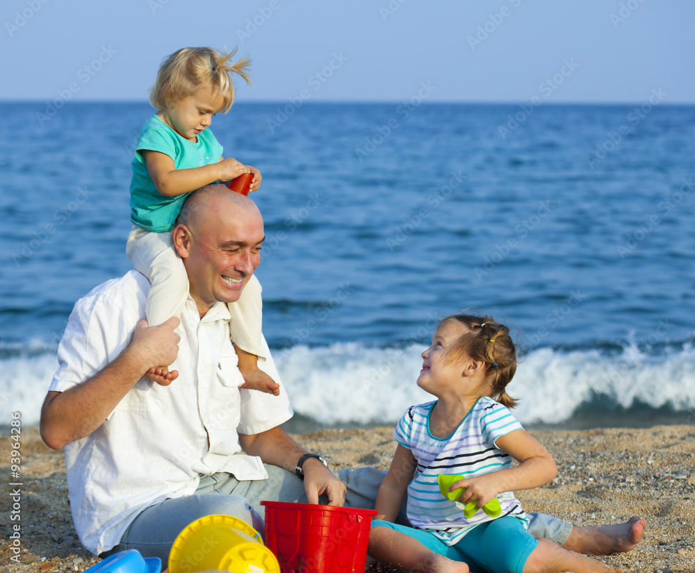 Fototapeta premium Dad and daughters on beach.