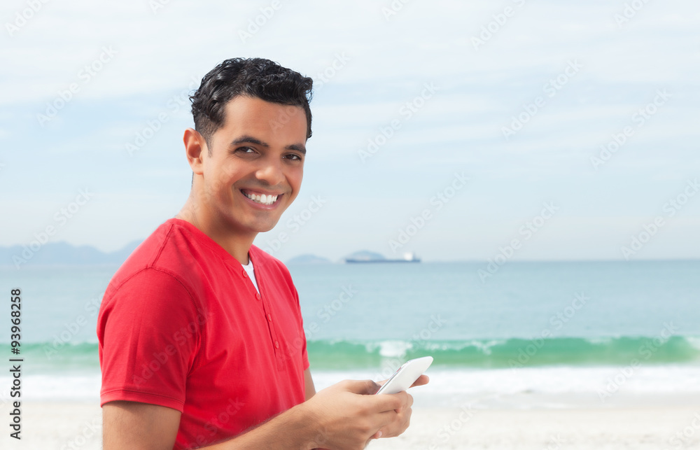 Latino im roten Shirt schreibt Nachricht mit dem Handy