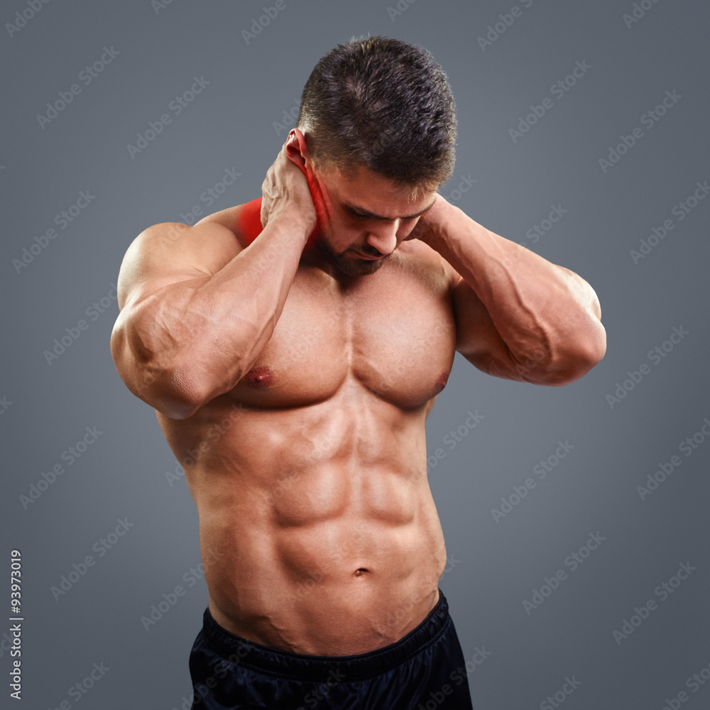 Muscular man suffering from neck pain. Front view over gray background Muscular man suffering from neck pain. Front view over gray background