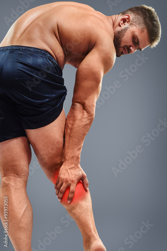 Muscle man having calf pain. Bodybuilder tension. Glowing red spot concept