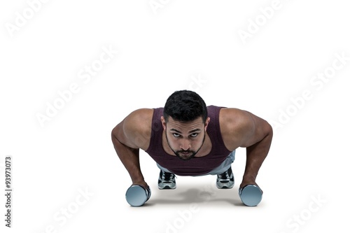 Muscular man doing push ups with dumbbells