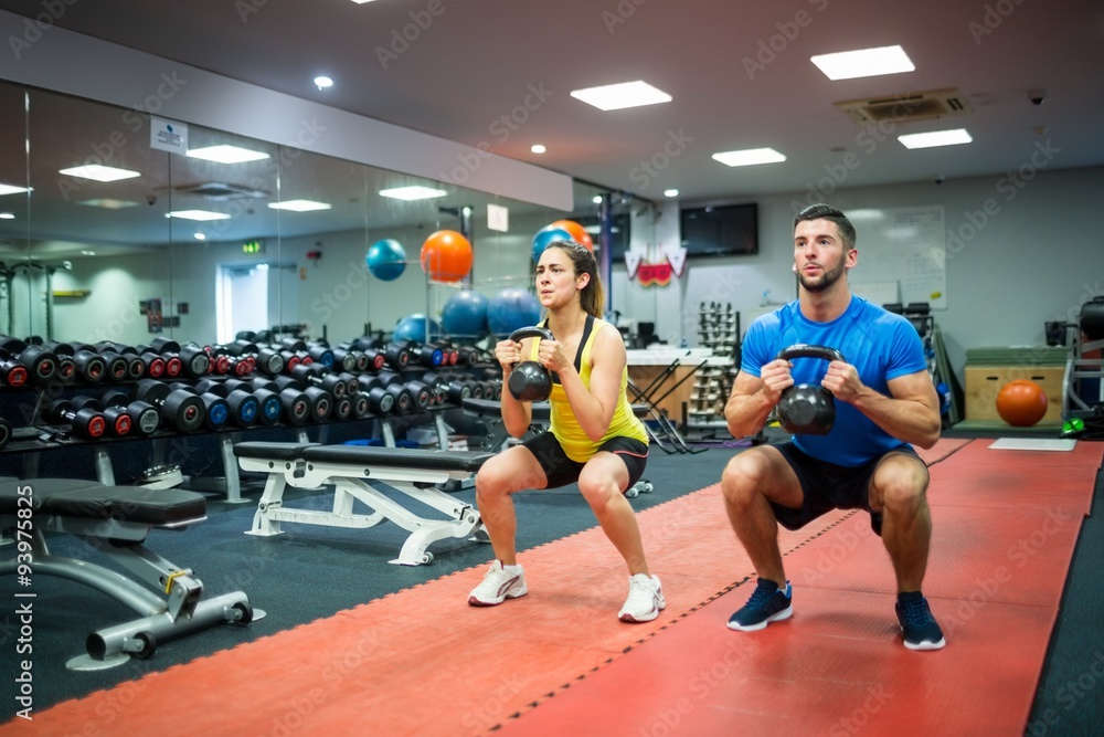 Man and woman working out using kettle bells Man and woman working out using kettle bells