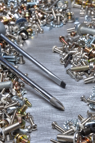 Screwdrivers and hardware bolts nuts washers screws on metal surface