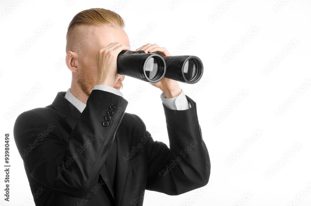 Business and search topic: Man in black suit holding a black binoculars in hand on white isolated background in studio Business and search topic: Man in black suit holding a black binoculars in hand on white isolated background in studio
