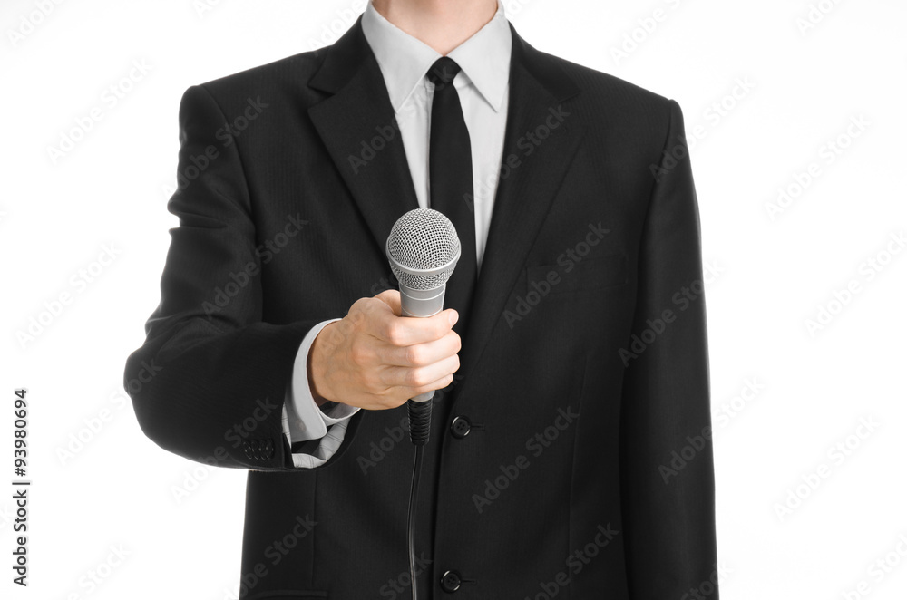 Business and speech topic: Man in black suit holding a gray microphone on an isolated white background in studio Business and speech topic: Man in black suit holding a gray microphone on an isolated white background in studio