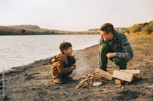 father and son burning fires on the lake