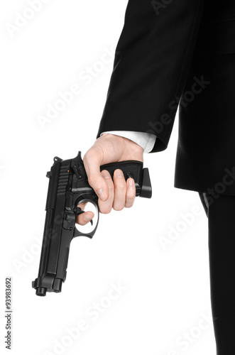 Firearms and security topic: a man in a black suit holding a gun on an isolated white background in studio
