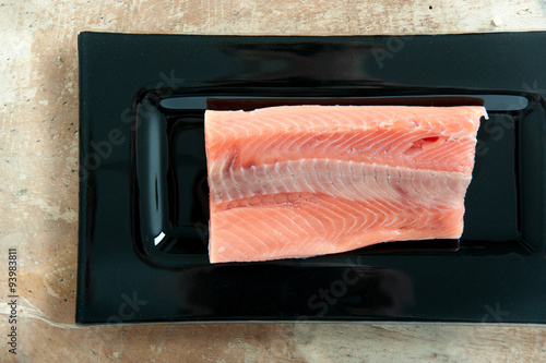 Raw salmon fillet on dark glass rectangular dish (top view)