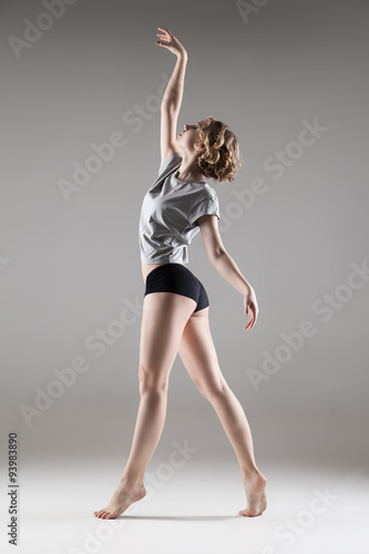young beautiful woman in grey T-shirt and black shorts dancing