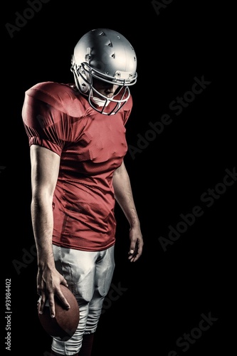 American football player with ball looking down