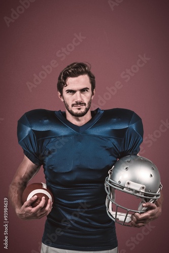 Confident american football player holding helmet and ball