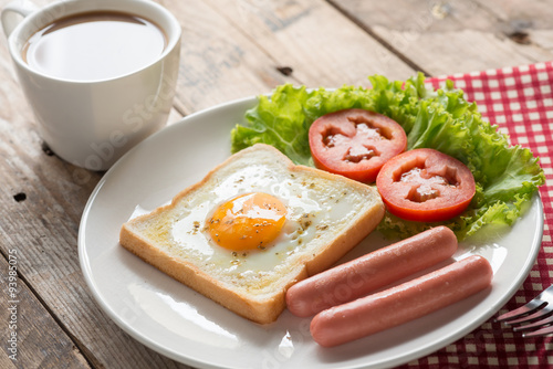 Fried toast with egg, sausage and a cup coffee.