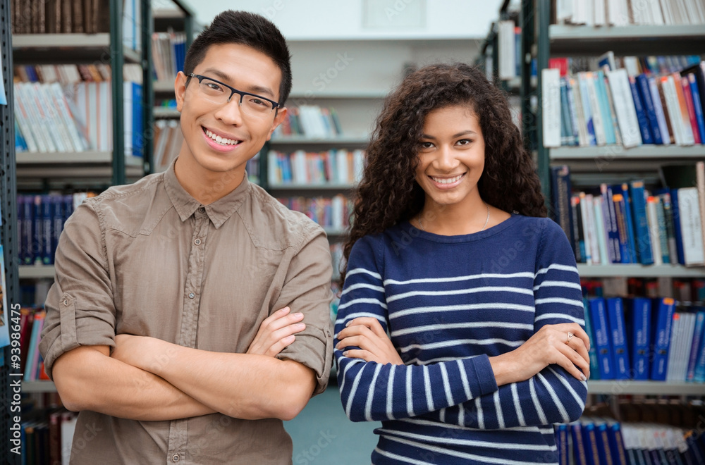 Happy students standing in library Happy students standing in library
