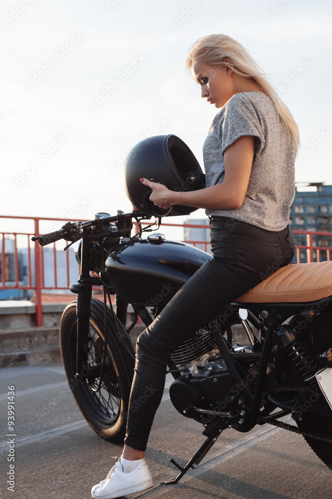 Naklejka premium Biker girl sitting on vintage custom motorcycle