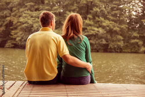 couple sitting by the water and hugging 