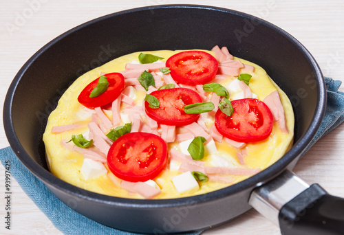 omelet with ham and cheese in a frying pan