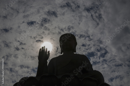 The Tian Tan Buddha in Hong Kong in a miracle sun light and dramatic sky background.