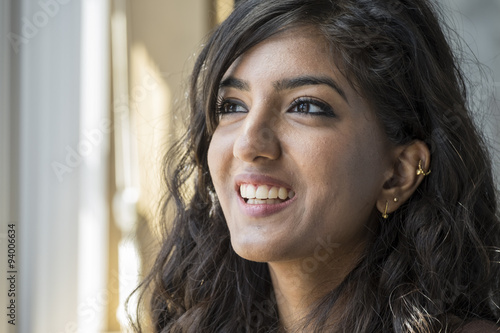 Portrait of a young middle eastern woman, smiling, in window light