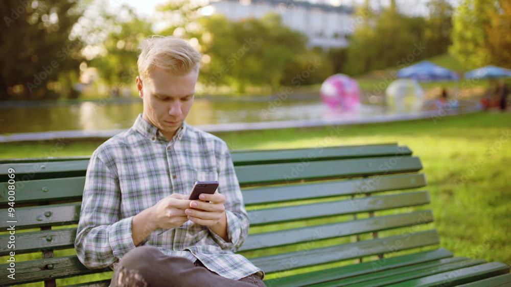 Happy boy sitting in the park and texting on smartphone
Happy boy sitting in the park and texting on smartphone