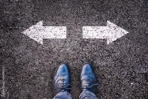 Fotografie Feet and two arrows painted on an asphalt road, choice and division, society pol