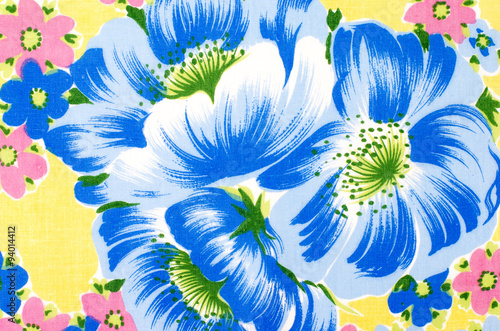 Floral pattern on yellow fabric. Colorful exotic big blue flower with small pink flowers print as background.