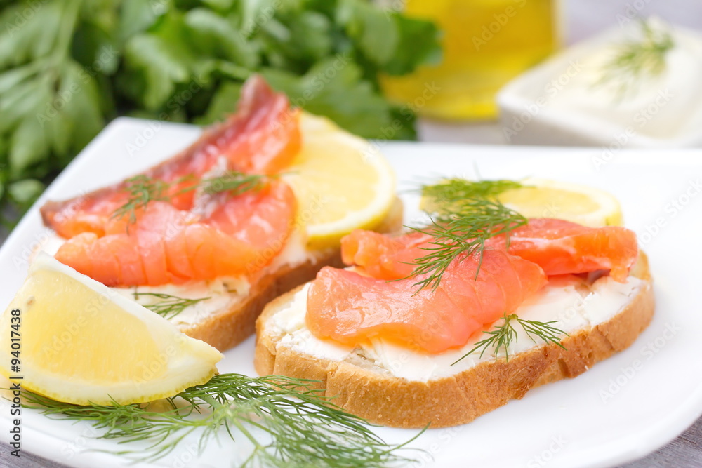 Sandwich with smoked salmon, cream cheese and lemon on plate Sandwich with smoked salmon, cream cheese and lemon on plate