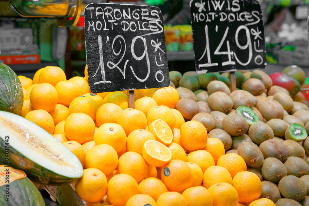 Bench of oranges and kiwi in a spanish market with a price list