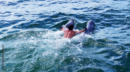 The man ride on dolphins in ocean